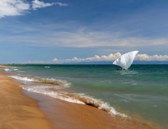 menschenleerer Strand mit einem kleinem Boot im Wasser am Lake Tanganyika